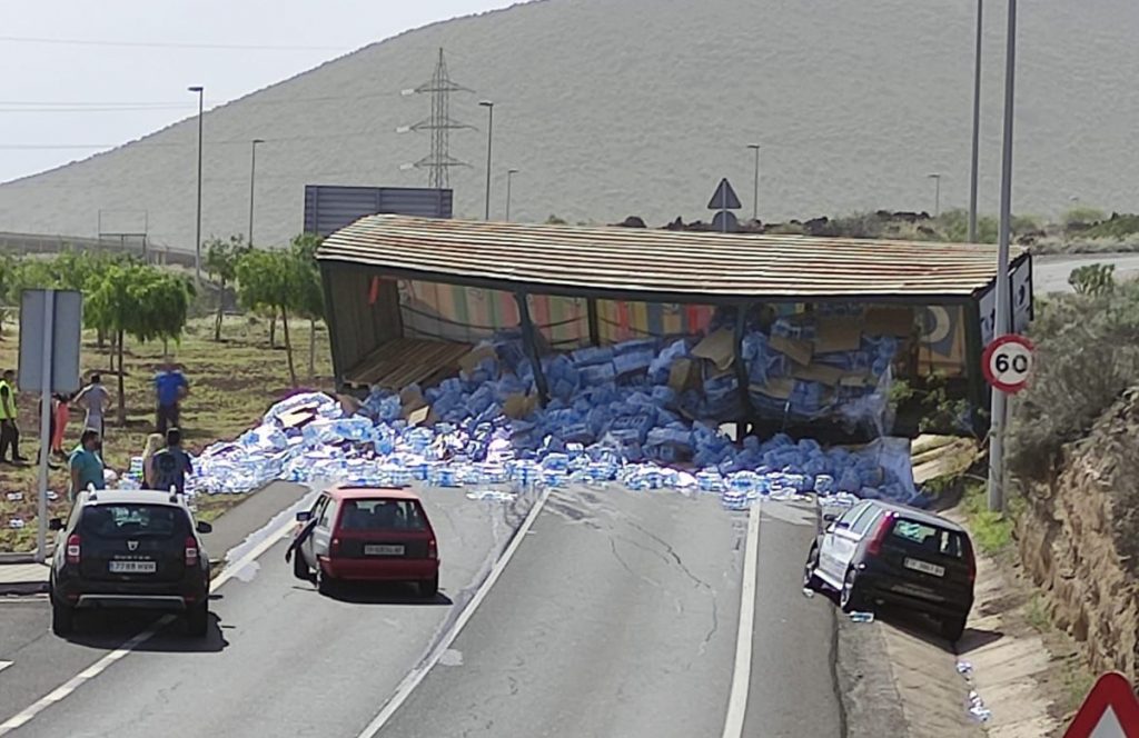A lorry sheds its load of water bottles and blocks road in Arafo