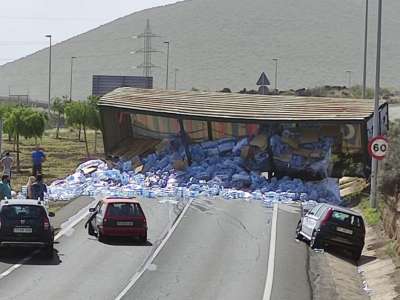A lorry sheds its load of water bottles and blocks road in Arafo