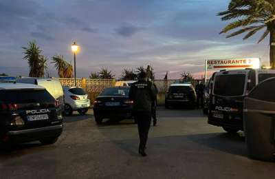 A corpse without head or hands is washed up on a beach in front of a restaurant 