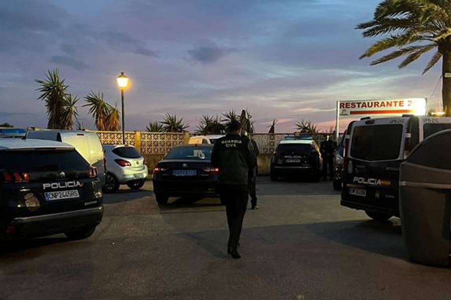 A corpse without head or hands is washed up on a beach in front of a restaurant 