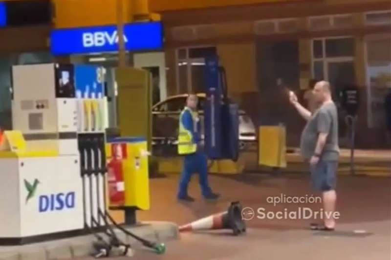 Man pulls out hoses and lights a lighter at a petrol station in the Canary Islands