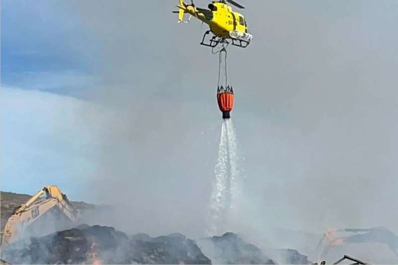 Firefighters use diggers and helicopters to combat the compost plant fire in Tenerife